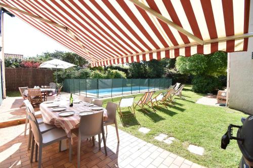 une terrasse avec une table et des chaises sous un parasol dans l'établissement Hossegor Charmante villa avec piscine, jardin et dépendance pour 15 personnes., à Hossegor