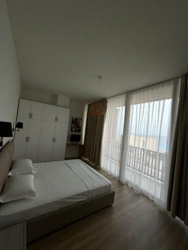 a bedroom with a large bed and a large window at Whisky Green Coast Hotel & Apartments in Palasë