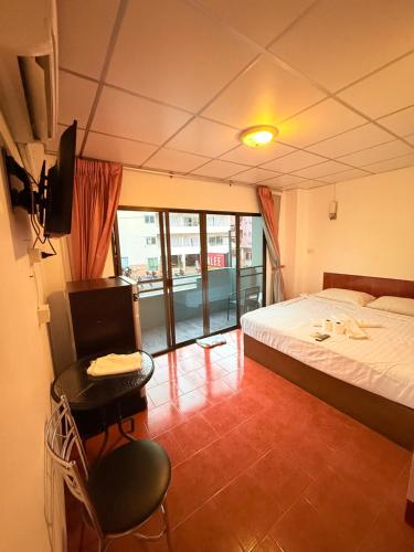 a bedroom with a bed and a chair and a television at Malee Guesthouse & Restaurant in Pattaya