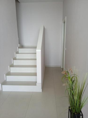 a staircase in a white room with potted plants at Whisky Green Coast Hotel & Apartments in Palasë