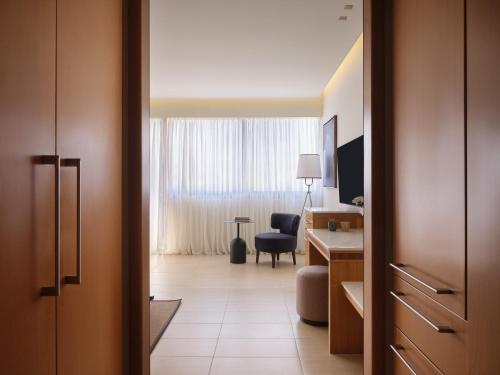 a hotel room with a desk and a chair in a room at Atlantica Oasis Hotel in Limassol