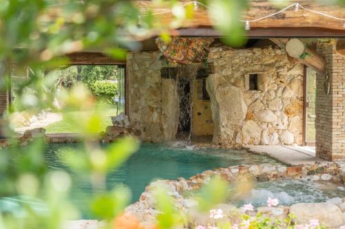 a swimming pool with a waterfall in a stone building at Luxury villa Colle dell'Asinello ,proprietari ,Villa In esclusiva near ORVIETO in Guardea