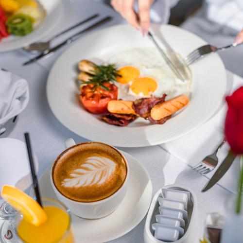 a table with two plates of food and a cup of coffee at Solymar Hotel & Beach in Manama