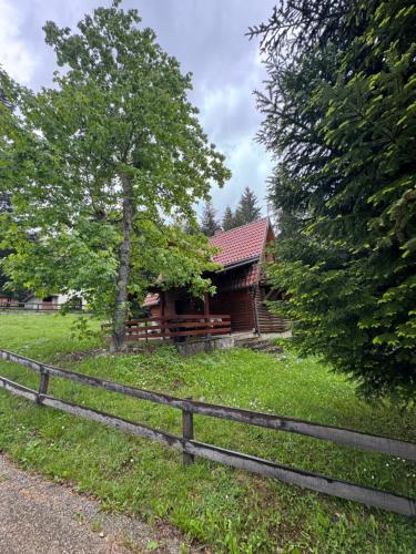 a log cabin with a fence and a tree at Čarobna kućica in Mitrovac