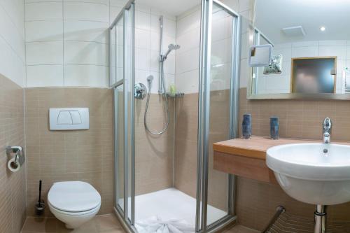 a bathroom with a shower and a toilet and a sink at Verwöhn-Wellnesshotel Walserhof in Hirschegg