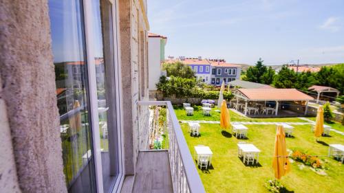 a balcony with a view of a yard with tables and chairs at Limonata Bozcaada ex Vina Garden in Bozcaada