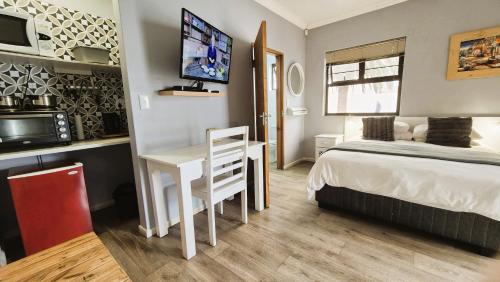 a bedroom with a bed and a desk and a tv at Tiende Laan Bed & Breakfast and Self-Catering in Walvis Bay
