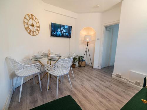 a dining room with a table and chairs and a clock at Business Leisure Near Canary Wharf Free Parking in London