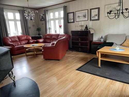 a living room with red leather furniture and wooden floors at Villa Tullgatan Borgholm in Borgholm
