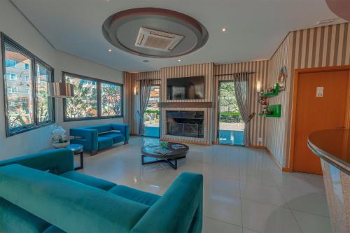a living room with blue couches and a fireplace at Hotel Laghetto Viale in Gramado
