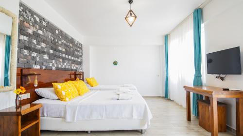 a bedroom with a white bed with yellow pillows at Limonata Bozcaada ex Vina Garden in Bozcaada