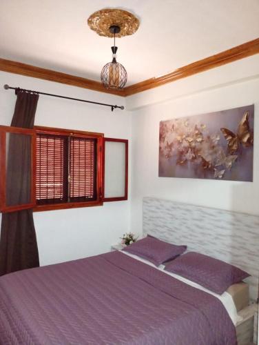 a bedroom with a purple bed and a window at Mhamid airport in Marrakech