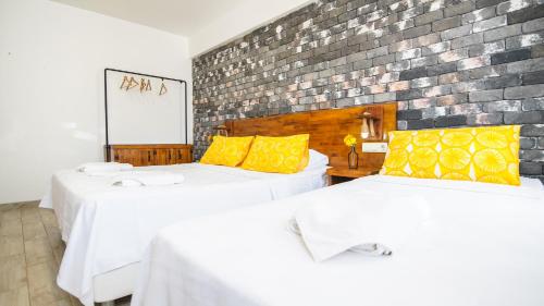 two beds in a room with a brick wall at Limonata Bozcaada ex Vina Garden in Bozcaada