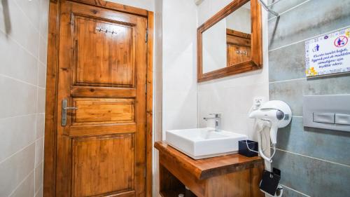 a bathroom with a sink and a wooden door at Limonata Bozcaada ex Vina Garden in Bozcaada