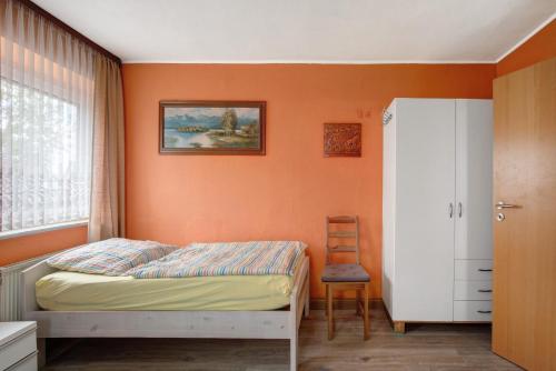 a bedroom with orange walls and a bed and a chair at Haus Steinheim in Dillingen an der Donau
