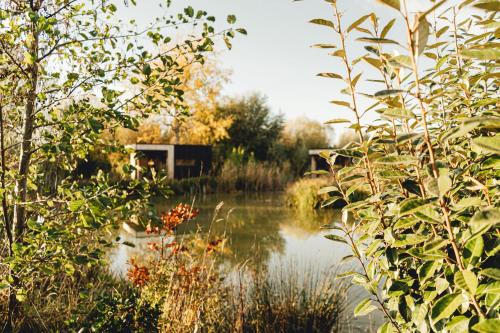 a body of water with a building in the background at Le Piloti in Saint-Quentin-en-Tourmont