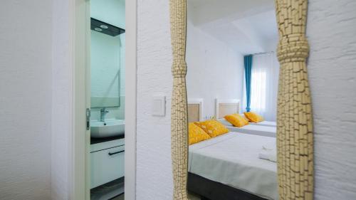 a bedroom with a bed with orange pillows and a mirror at Limonata Bozcaada ex Vina Garden in Bozcaada