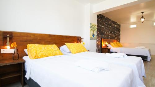a bedroom with two beds with white sheets and yellow pillows at Limonata Bozcaada ex Vina Garden in Bozcaada