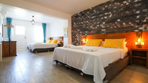 a bedroom with two beds and a brick wall at Limonata Bozcaada ex Vina Garden in Bozcaada