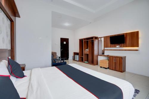 a bedroom with a large bed and a television at Townhouse Oak Padang near RTH Imam Bonjol formerly Bunda Hotel in Padang