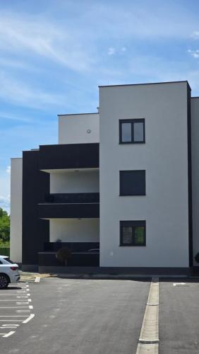 a white building with a parking lot in front of it at Apartman Jakov in Zagreb