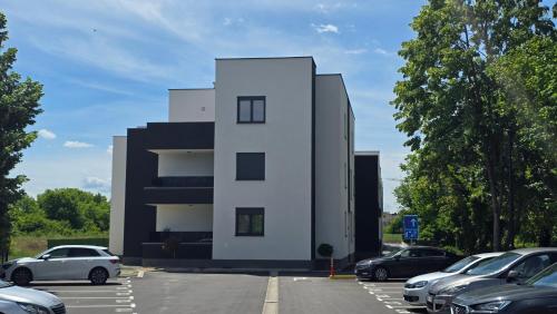 a white building with cars parked in a parking lot at Apartman Jakov in Zagreb