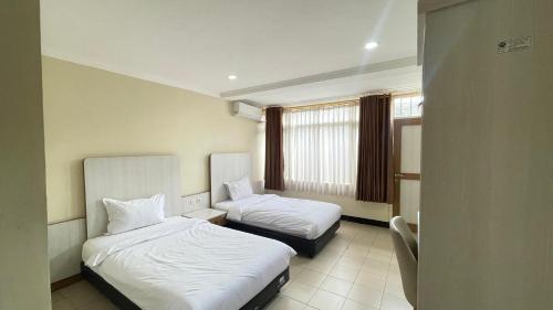 una camera d'albergo con due letti e una finestra di tekMIRA Hotel a Bandung