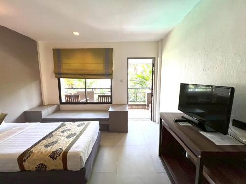 a bedroom with a bed and a flat screen tv at The Viridian Resort Patong in Patong Beach