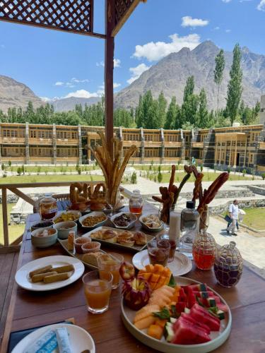 a table with plates of food on it with mountains in the background at Rivage Resort Skardu in Shigar