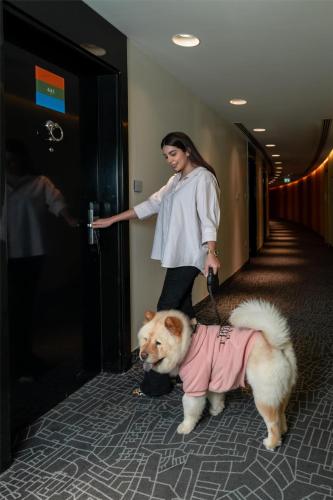 a woman standing next to a dog in a hallway at Park Inn by Radisson Dubai Motor City in Dubai