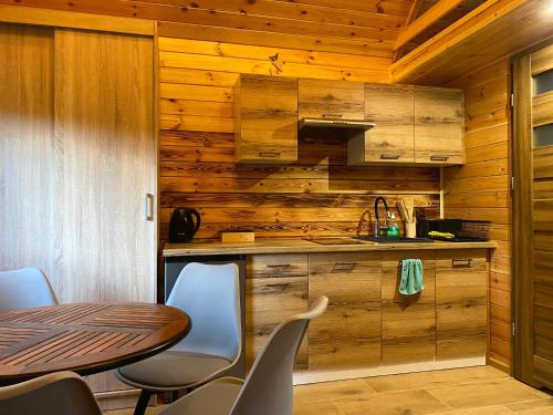 a kitchen with a table and chairs and wooden walls at Leśna Przystań Nowy Kobrzyniec in Kobrzyniec Nowy