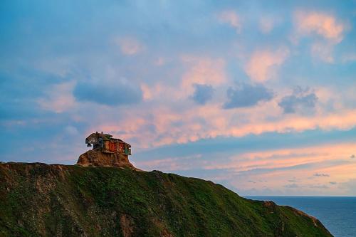 a house on top of a hill on the ocean at Oceanfront Coastal Home with Breathtaking Views Hiking Beaches & More in Moss Beach