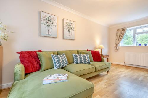 a living room with a green couch with red pillows at Cornerways by Bloom Stays in Canterbury