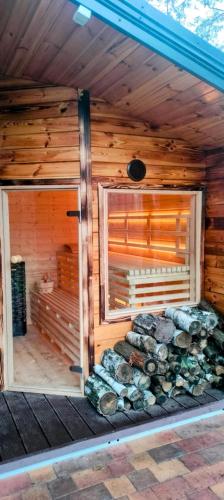 a wooden cabin with a pile of logs in it at Leśna Przystań Nowy Kobrzyniec in Kobrzyniec Nowy