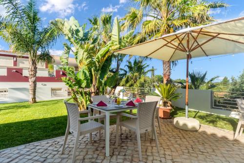 a patio with a table and chairs and an umbrella at Hotel Rural Brícia Du Mar in Ferragudo