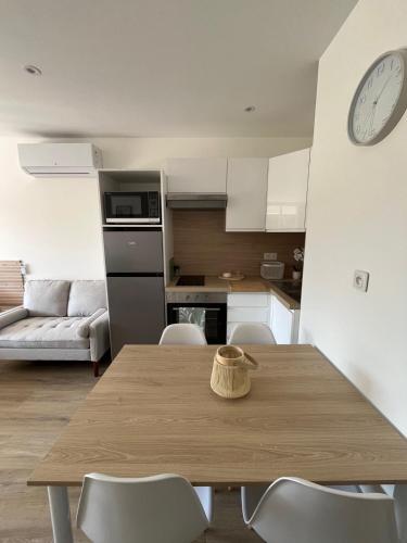 une cuisine avec une table en bois, des chaises et une horloge dans l'établissement Le nid de Mag, à Balaruc-les-Bains