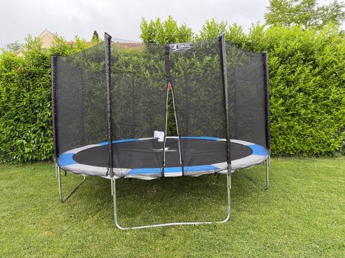 a trampoline with a black cover on the grass at L’escale du Roy : maison récente proche versailles in La Queue-lès-Yvelines