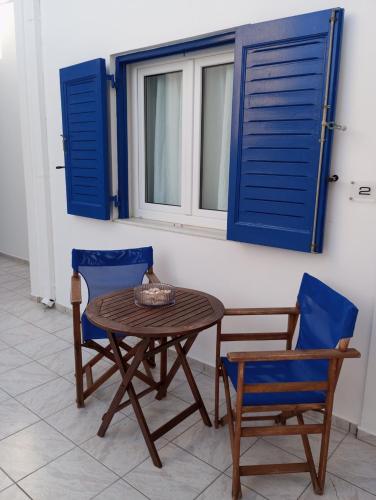 a table and two chairs and a window with blue shutters at Captain Stavros in Pollonia