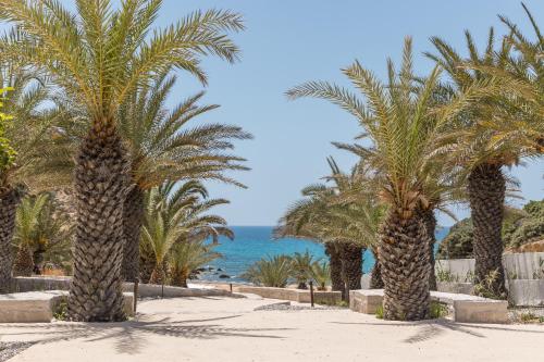 a row of palm trees on a beach with the ocean at Golden Milos Beach Ηouse by Domotel in Provatas