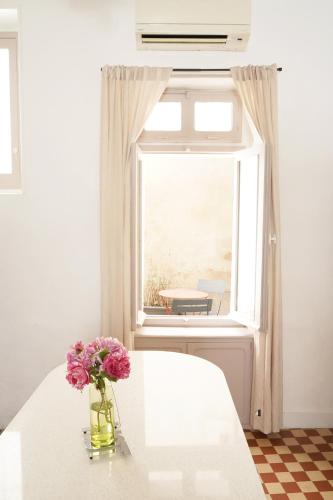 un vase de fleurs sur une table blanche avec une fenêtre dans l'établissement Appartement Centre-Ville, à Avignon
