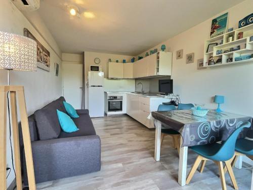 un salon avec un canapé et une table et une cuisine dans l'établissement Appartement T2 au bord de l'eau, à La Londe-les-Maures