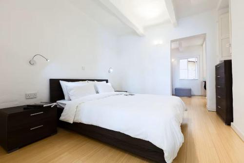 a bedroom with a large white bed and a wooden floor at Valletta Seafront in Valletta