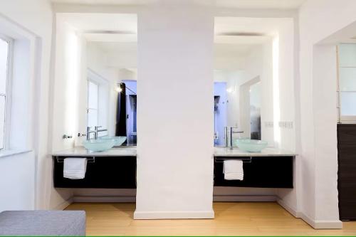 a bathroom with two sinks and two mirrors at Valletta Seafront in Valletta
