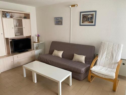 un salon avec un canapé, une table et une chaise dans l'établissement Appartement vue sur le port, proche mer, au Cap d'Agde