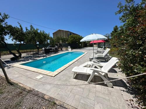 a swimming pool with two chairs and an umbrella at House Cefalù 1915 in Lascari