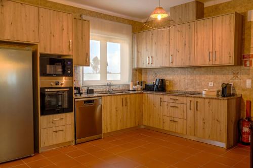 a kitchen with wooden cabinets and a window at QUINTA das OLIVEIRAS COUNTRY HOUSE in Marinhais