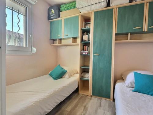 - 2 lits dans une petite chambre avec des armoires vertes dans l'établissement Appartement T2 au bord de l'eau, à La Londe-les-Maures