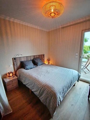 une chambre avec un lit et un lustre dans l'établissement Maison proche LA ROCHELLE & Ile de Ré, à Sainte-Soulle