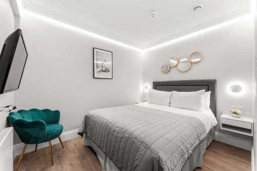a bedroom with a bed and a green chair at Cleveland Residences Russell Square in London