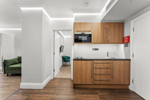 a kitchen with wooden cabinets and a green couch at Cleveland Residences Russell Square in London